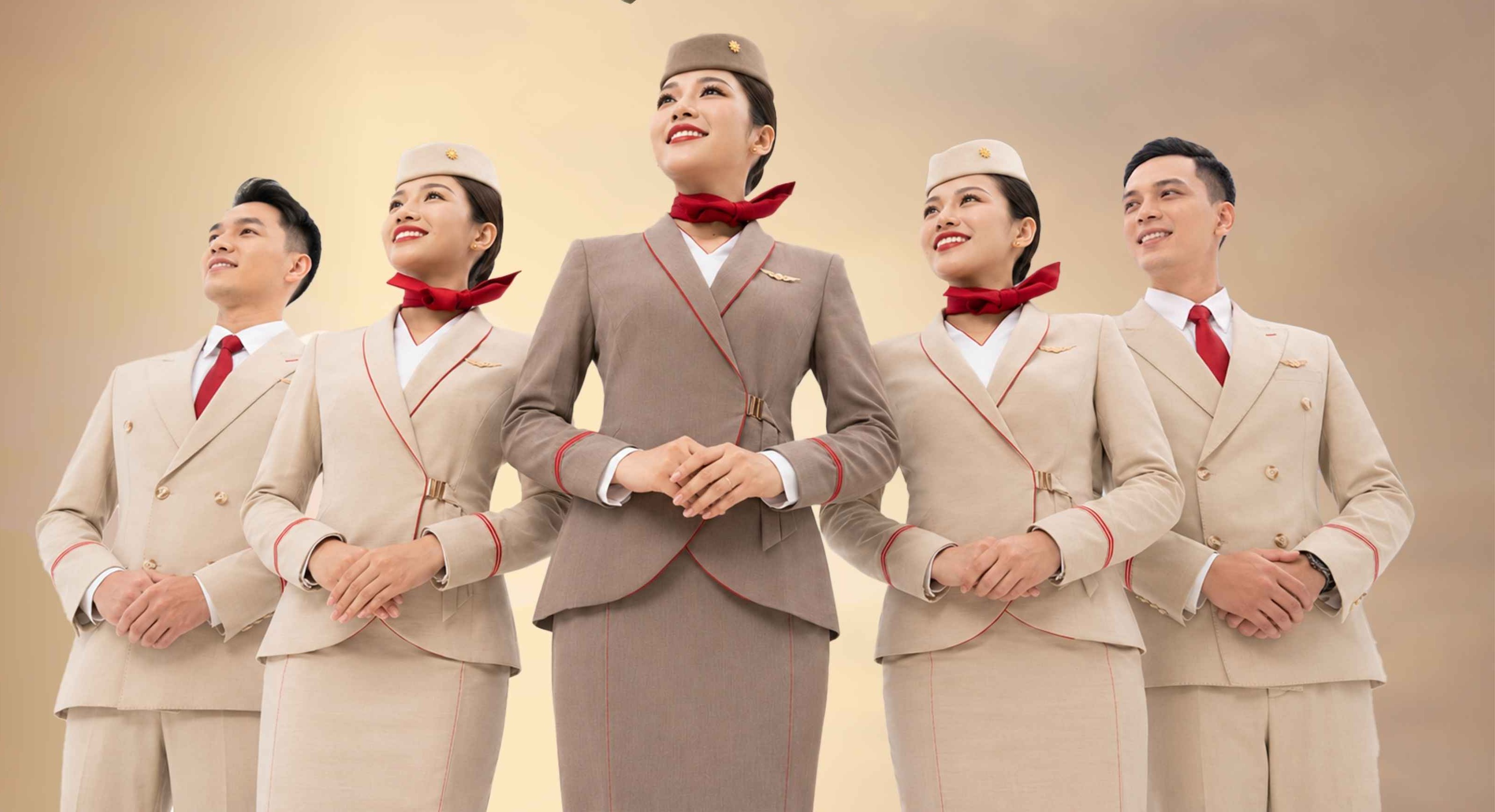 ลูกเรือ Sun PhuQuoc Airways ห้าคนในชุดยูนิฟอร์มสีครีมและน้ำตาล ยืนเรียงกันยิ้ม